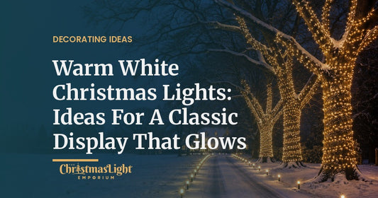 Three large oak trees along a snowy country driveway with trunks and limbs wrapped in warm white LED mini lights, the drive lined with warm white bulbs on ground stakes, at twilight in falling snow