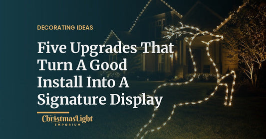 Front yard at night with glowing warm white wireframe deer on the lawn and a home with roofline Christmas lights behind them