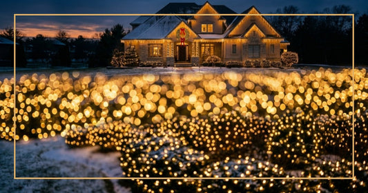 Upscale suburban home decorated with Christmas lights including net lights on bushes and icicle lights at dusk