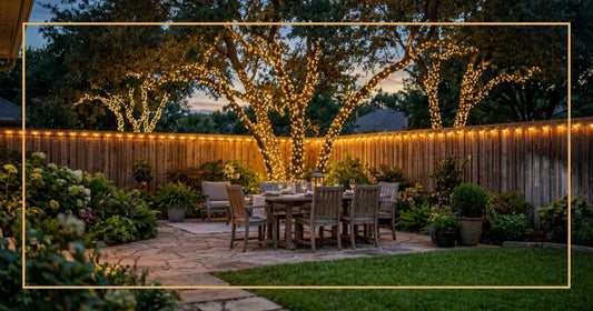 Backyard patio with a dining set and trees wrapped in warm white lights at dusk.