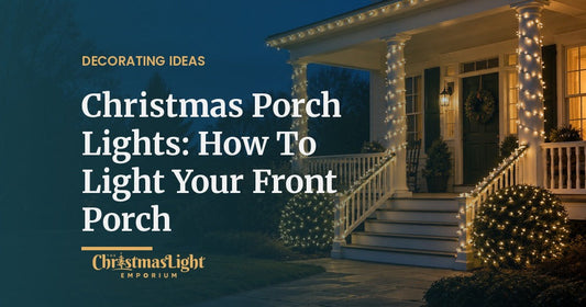 A white covered front porch at dusk with columns and stair railings wrapped in warm white mini lights, the porch roof edge outlined in warm white C7 bulbs, and shrubs by the steps covered in warm white net lights