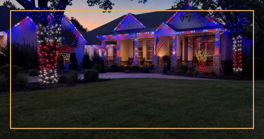 Suburban home at dusk with red white and blue LED lights on roofline trees and porch for 4th of July