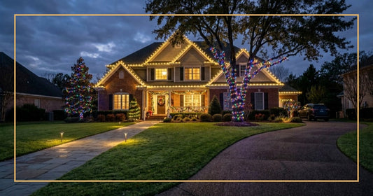 Brick home with warm white roofline lights, trees wrapped in multicolor lights and a lit front walkway at dusk.