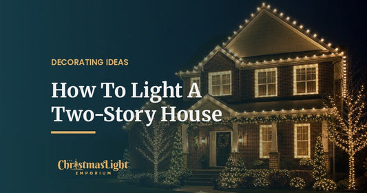 Two-story brick home at night with C9 bulbs along the upper roofline, lit second-story windows and wrapped trees in the front yard