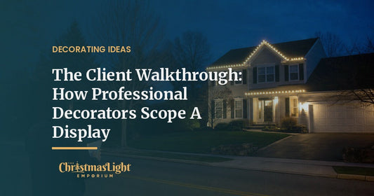 A person standing at the curb at dusk looking at a two-story home with warm white Christmas lights along part of the roofline
