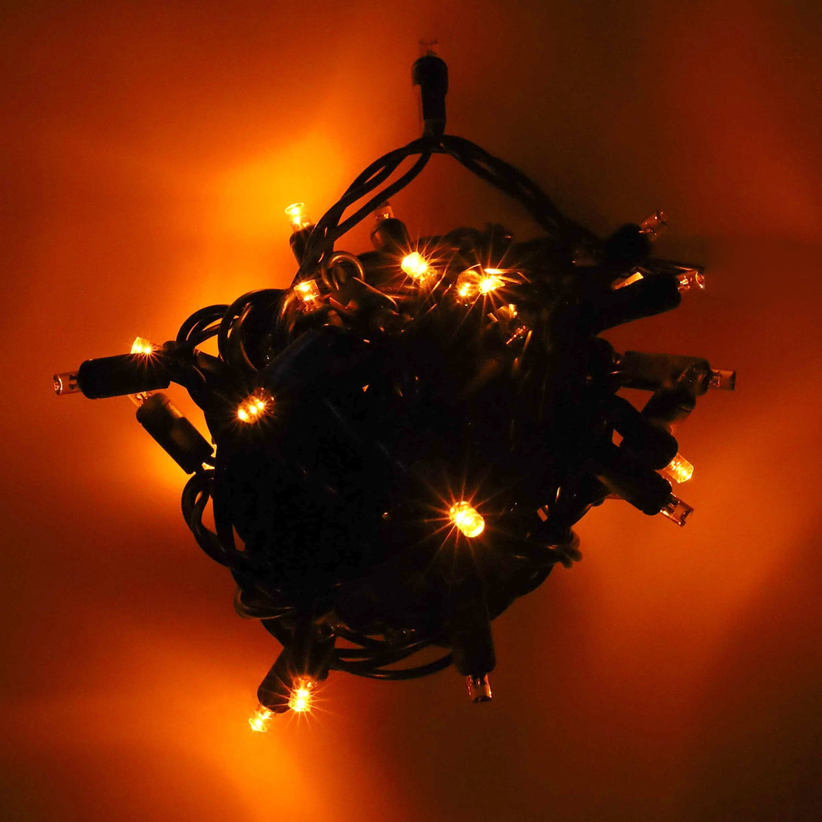 50 5mm Orange SuperSpark LED strobe Christmas lights lit in a bundle on a black background