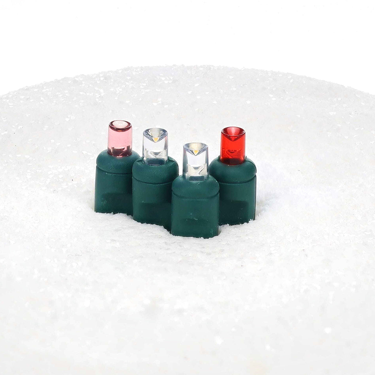 Unlit ColorCraft® Cupid 5mm LED lenses in pink, cool white, and red on green sockets set in white snow
