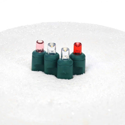 Unlit ColorCraft® Cupid 5mm LED lenses in pink, cool white, and red on green sockets set in white snow