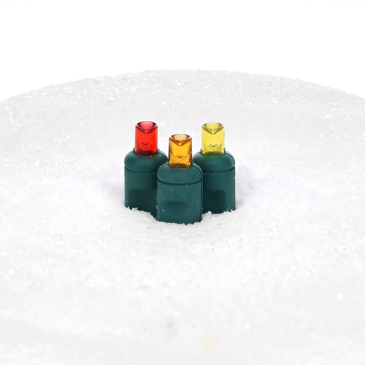 Unlit ColorCraft® Harvest 5mm LED lenses in red, orange, and gold on green sockets set in white snow