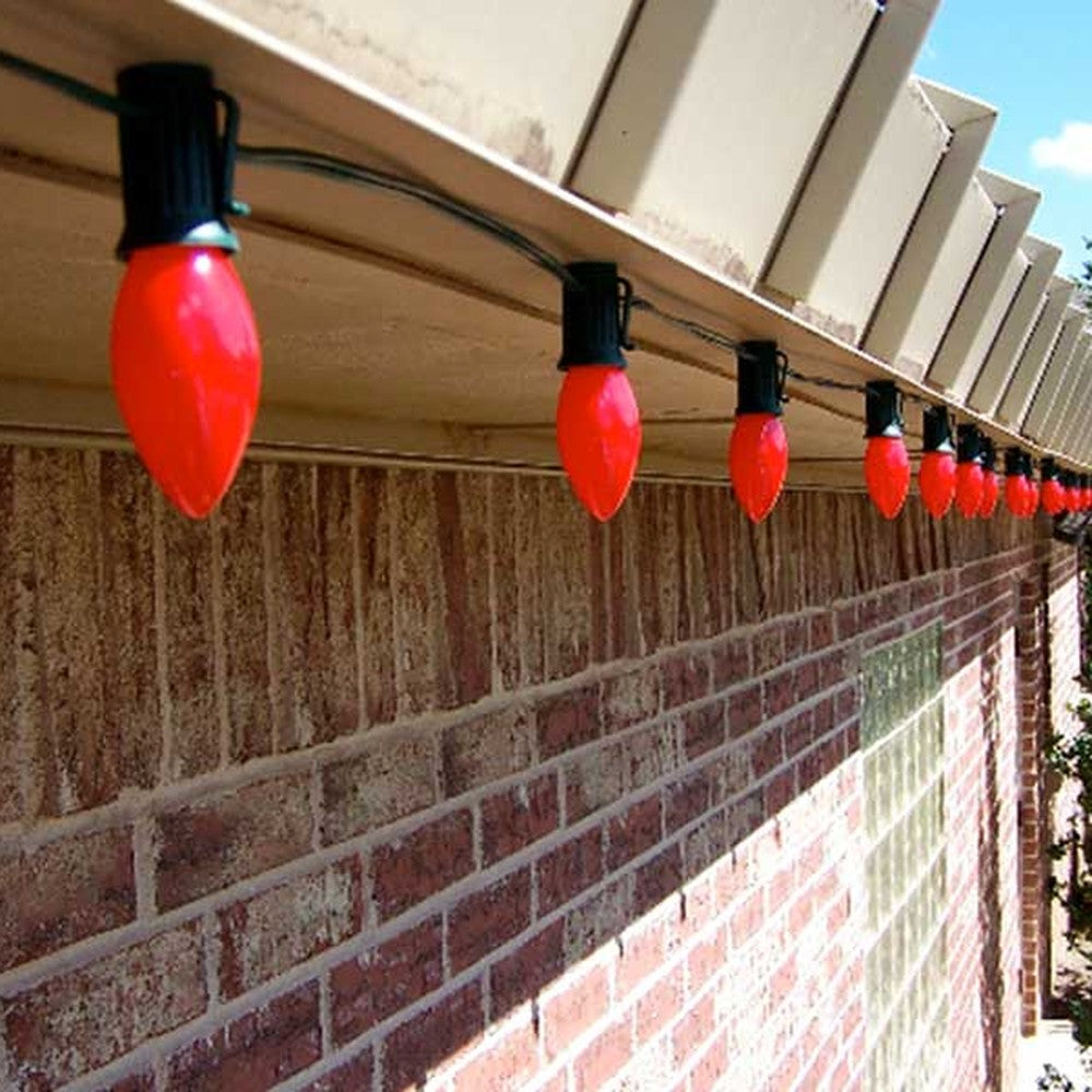 Row of red C9 bulbs in Lite-Netics magnetic sockets along a metal roofline on a brick building