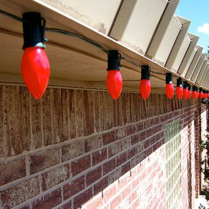Row of red C9 bulbs in Lite-Netics magnetic sockets along a metal roofline on a brick building