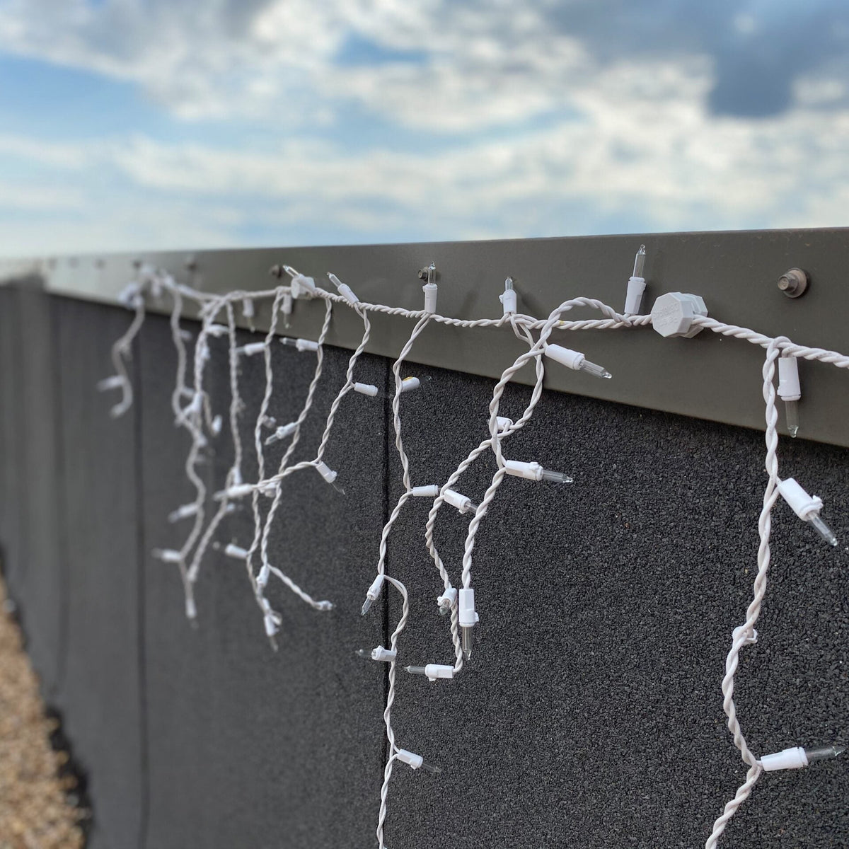 White icicle lights held along a metal fascia with Lite-Netics magnetic wire clamps