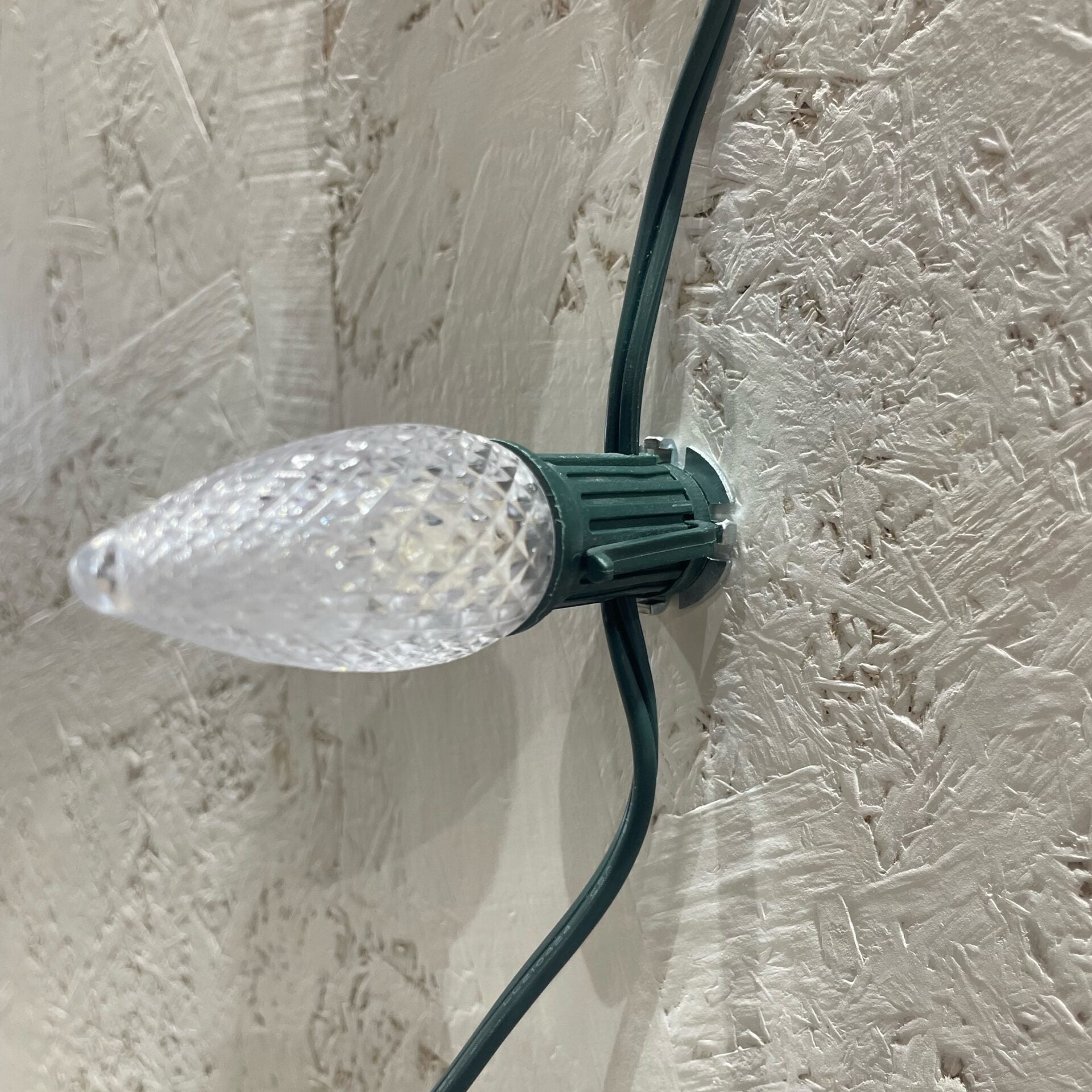 Lite-Netics magnetic C9 socket with LED bulb held by a nickel clip on a stucco wall